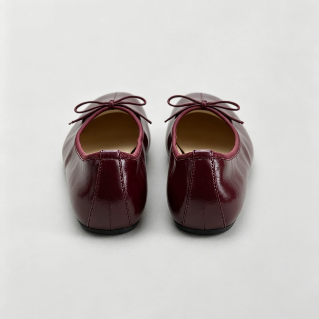 Pair of maroon shoes with laces on a light gray background