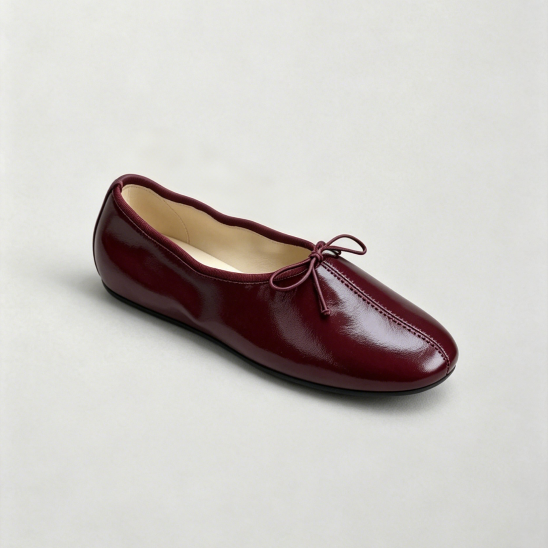 Burgundy flat shoe with a bow on a light gray background