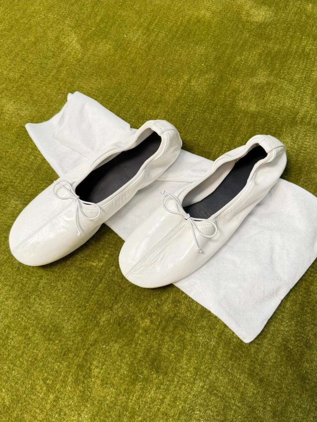White loafers with a bow on a white towel on a green surface