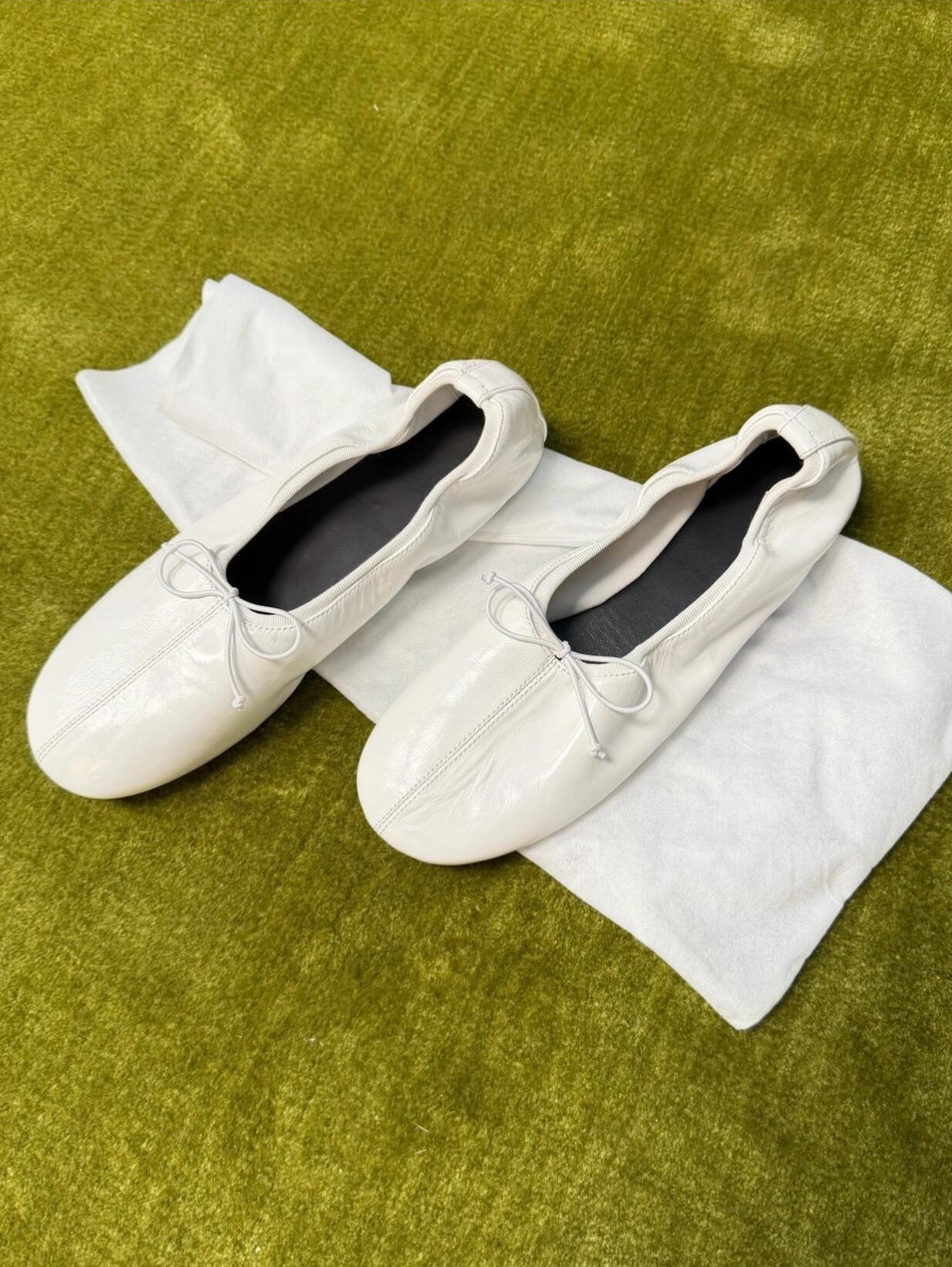 White loafers with a bow on a white towel on a green surface