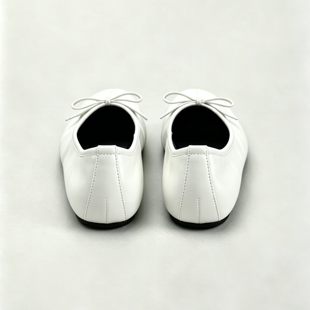 Pair of white shoes with black soles on a light gray background