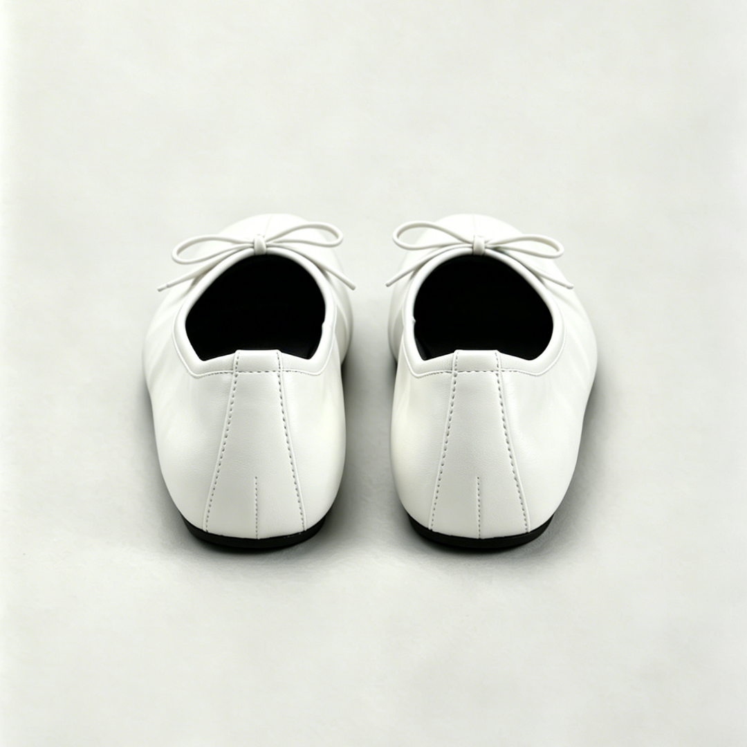 Pair of white shoes with black soles on a light gray background