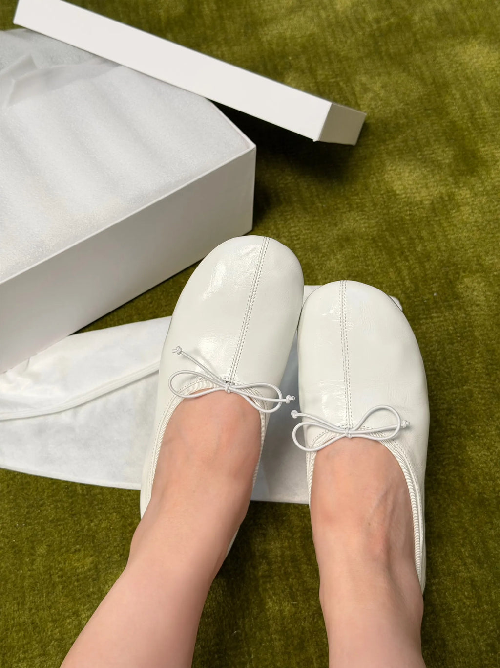 White shoes with bow details on a green surface