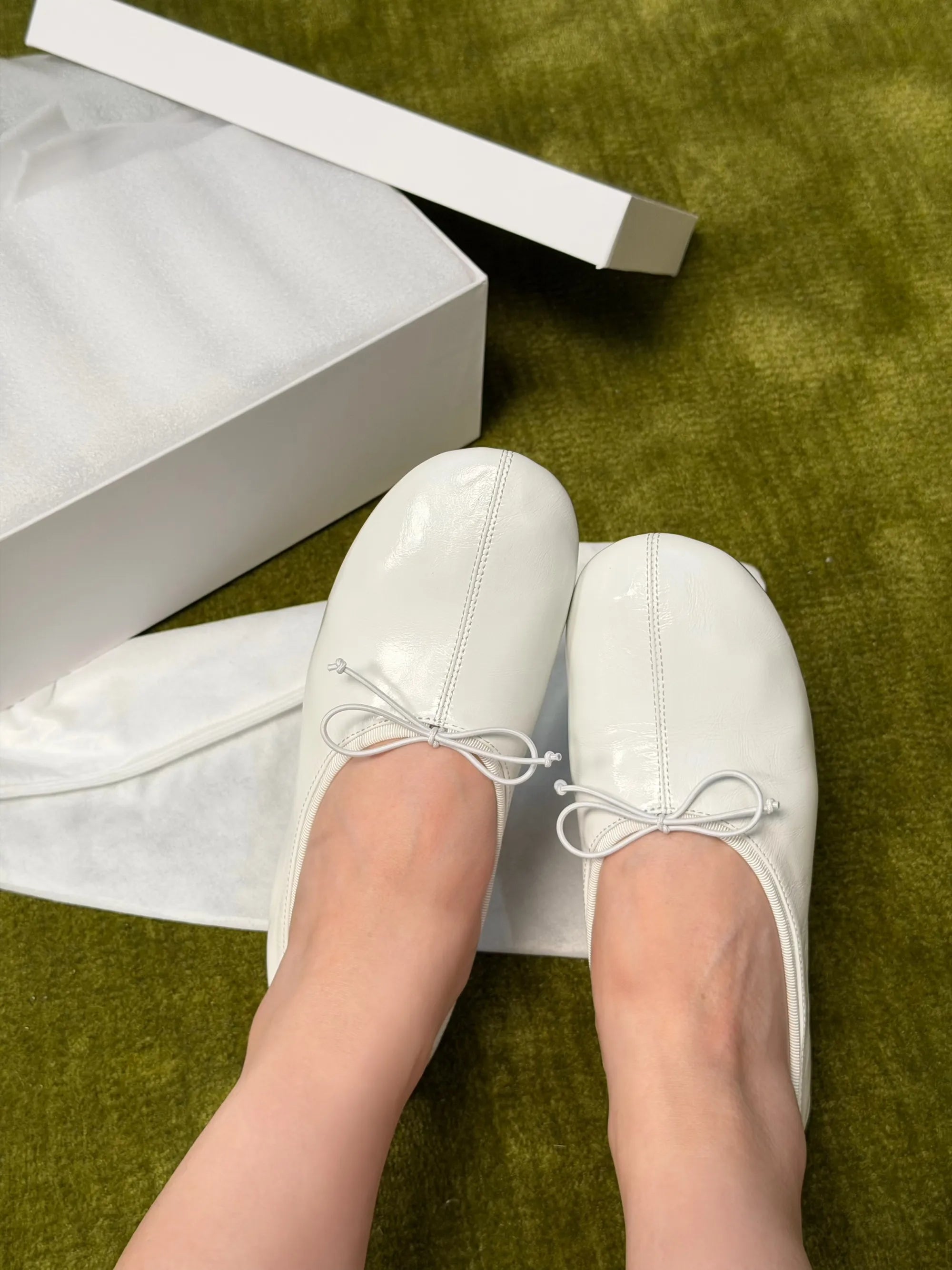 White shoes with bow details on a green surface