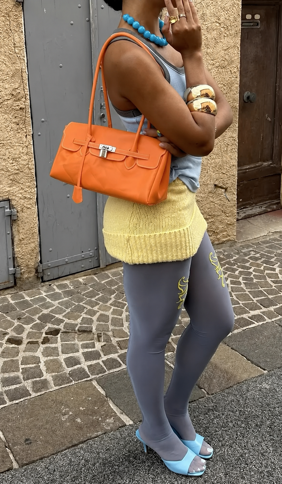 Jelly Firkin 36 JPG Shoulder Bag Tangerine worn on street with textured wall