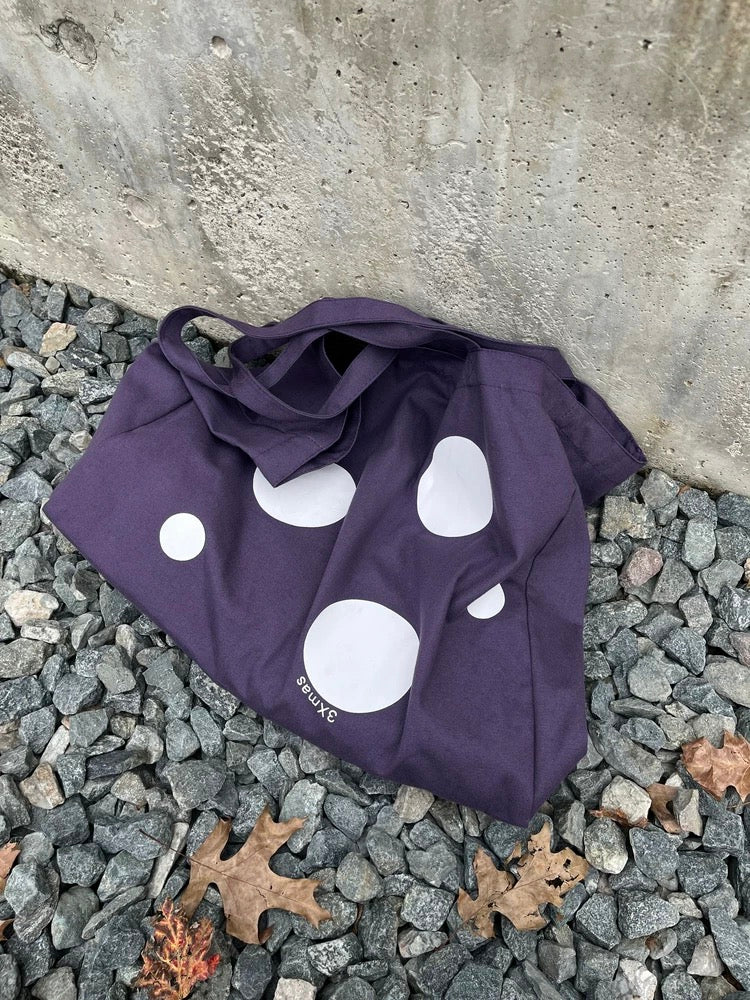 Purple bag with white polka dots on a stone surface