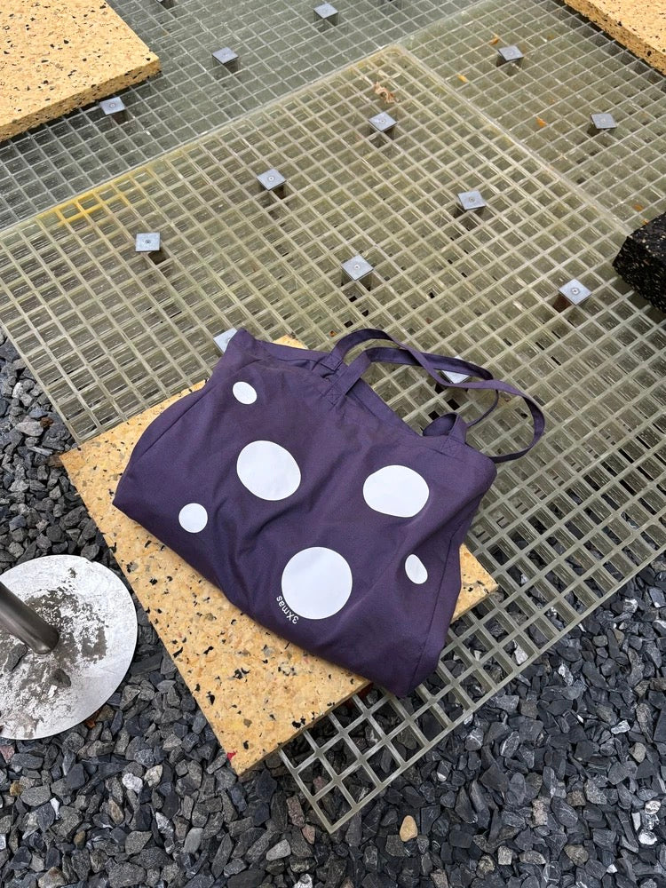 Purple tank top with white polka dots on a textured surface