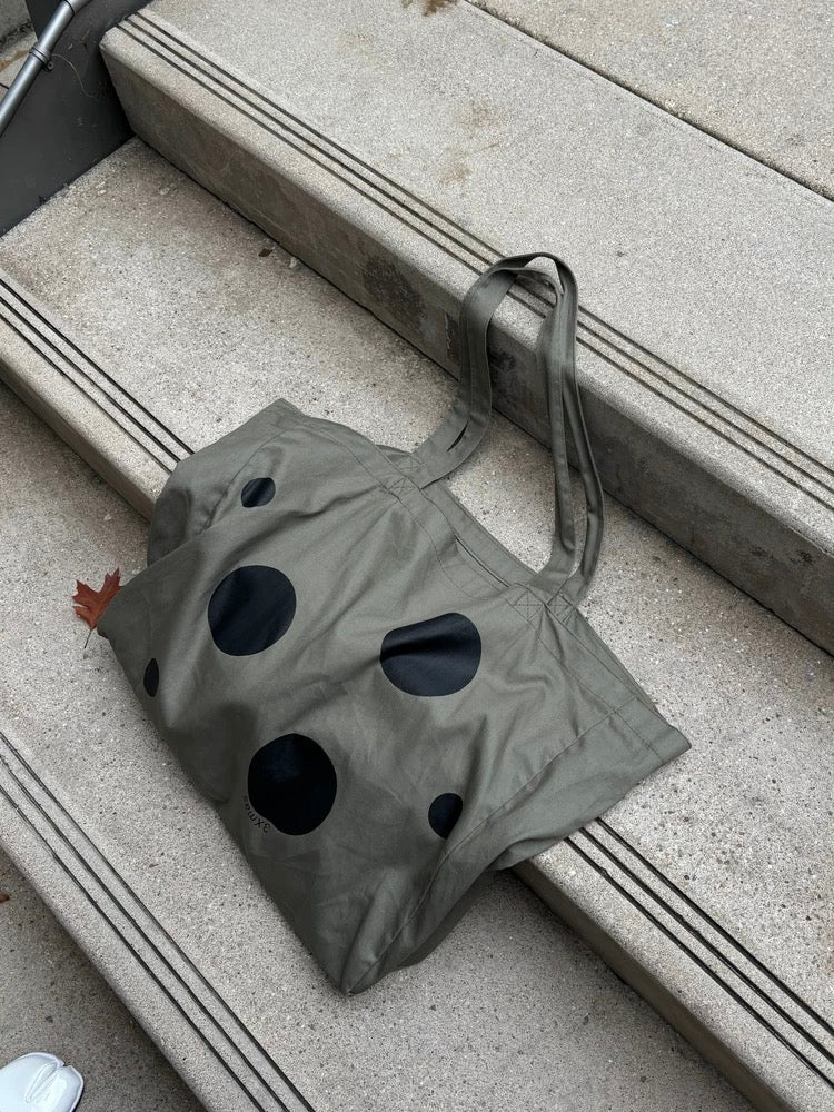 Gray bag with black circular holes on a concrete step